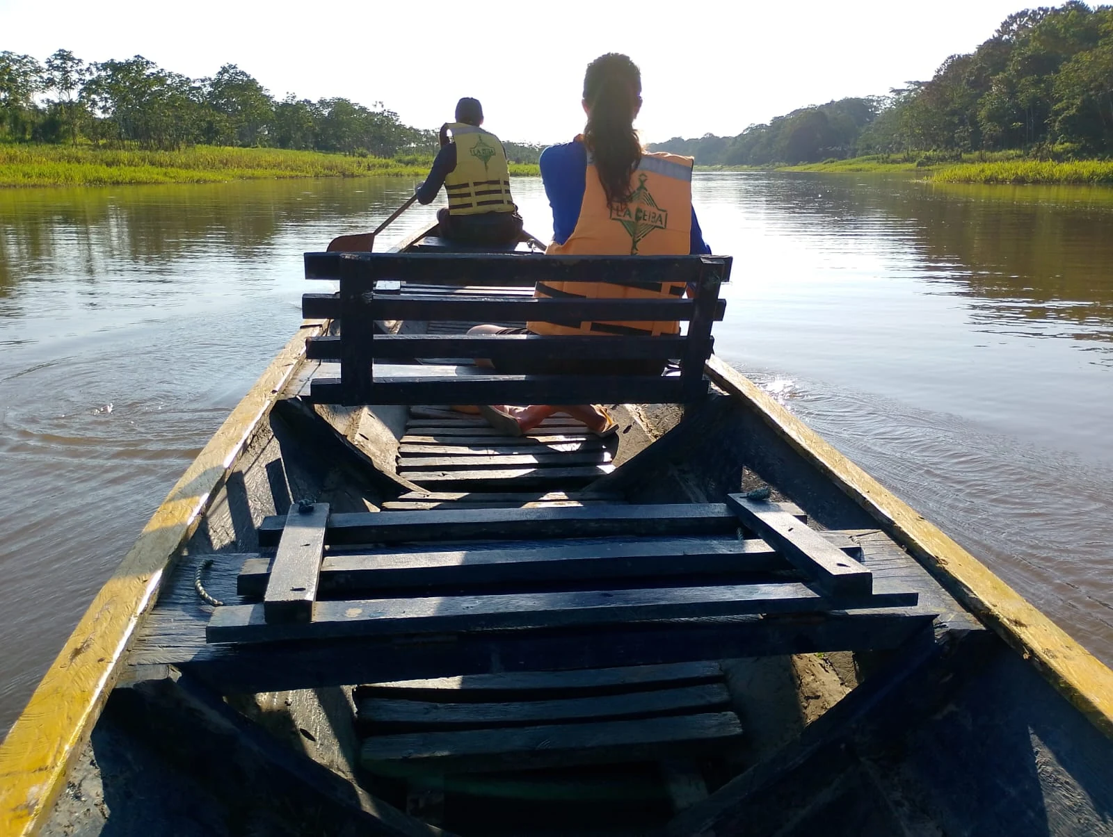 Canoa de madera navegando por un río tranquilo rodeado de selva amazónica