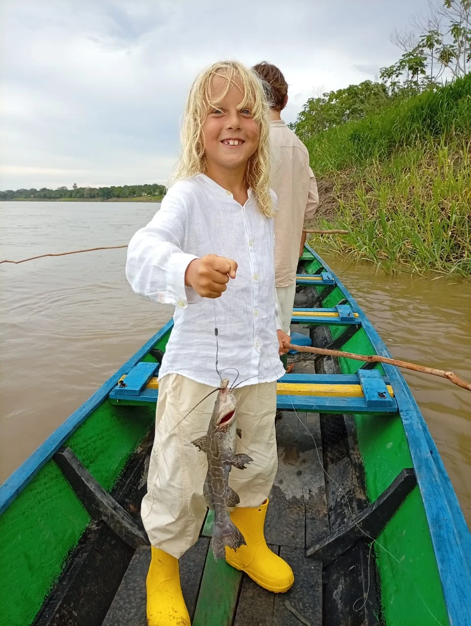 Viajera mostrando su pesca desde una canoa junto a la orilla
